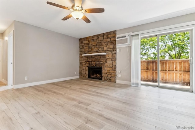 381 S Ames St Unit E104, Lakewood, CO 80226 - unfurnished living room with a ceiling fan, a stone fireplace, wood finished floors, and a wall unit AC