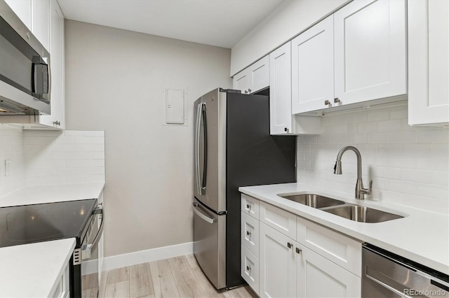 381 S Ames St Unit E104, Lakewood, CO 80226 - kitchen with stainless steel appliances, white cabinetry, decorative backsplash, and light countertops
