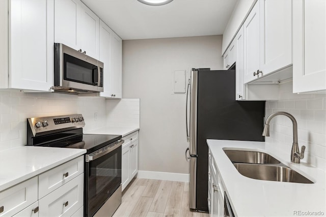 381 S Ames St Unit E104, Lakewood, CO 80226 - kitchen with stainless steel appliances, white cabinets, light wood-style flooring, and light countertops