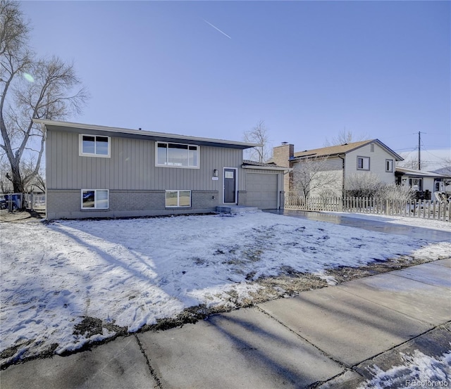 snow covered rear of property featuring a garage