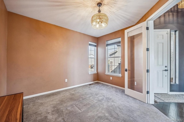 carpeted empty room with a chandelier