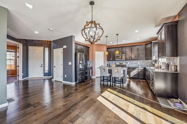 kitchen featuring dark hardwood / wood-style floors, appliances with stainless steel finishes, decorative light fixtures, and a kitchen island