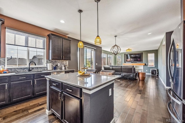 kitchen featuring a center island, stainless steel fridge with ice dispenser, dark hardwood / wood-style flooring, light stone counters, and tasteful backsplash