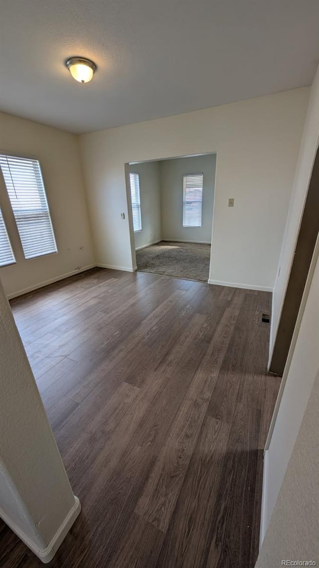 unfurnished room featuring a wealth of natural light and dark hardwood / wood-style flooring