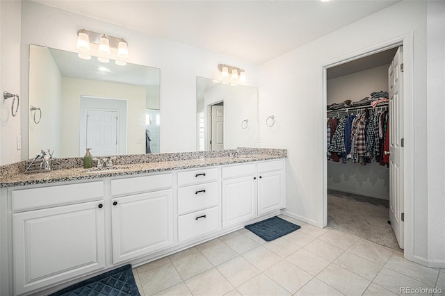 bathroom with a spacious closet, double vanity, tile patterned flooring, and a sink