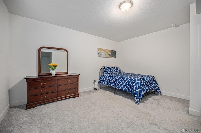 bedroom with light carpet, a textured ceiling, and baseboards