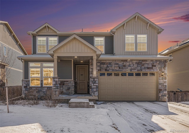 view of front of house with a garage, stone siding, board and batten siding, and fence