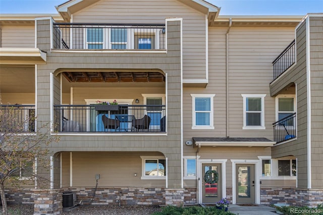 view of front of house with central AC unit and a balcony