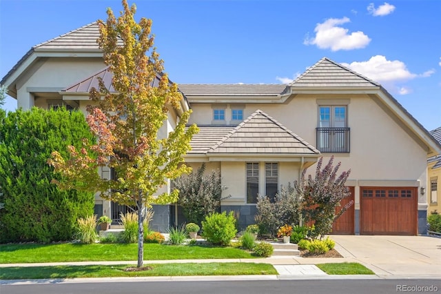 view of front facade featuring driveway, a front yard, a tile roof, and stucco siding