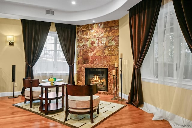 sitting room featuring a fireplace, a tray ceiling, and hardwood / wood-style floors