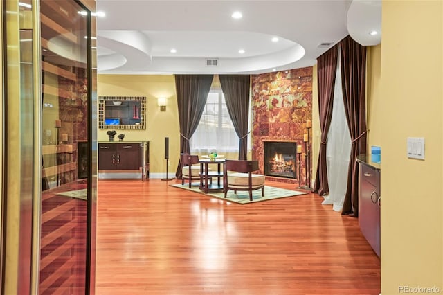 interior space featuring wood-type flooring, a high end fireplace, and a raised ceiling