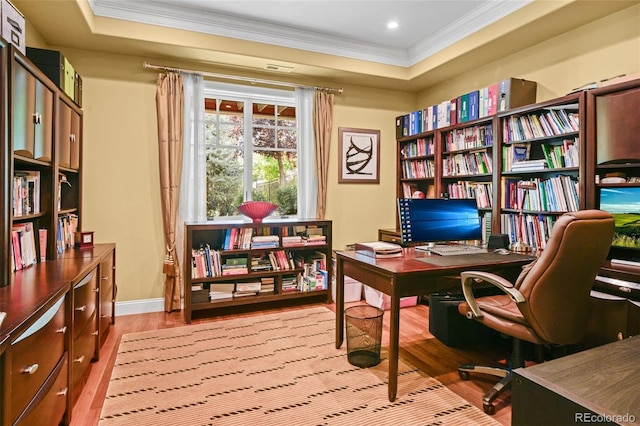 office space with crown molding, a tray ceiling, and light hardwood / wood-style flooring