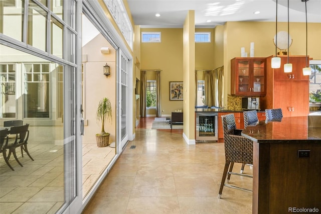 kitchen with a breakfast bar, wine cooler, hanging light fixtures, and a healthy amount of sunlight