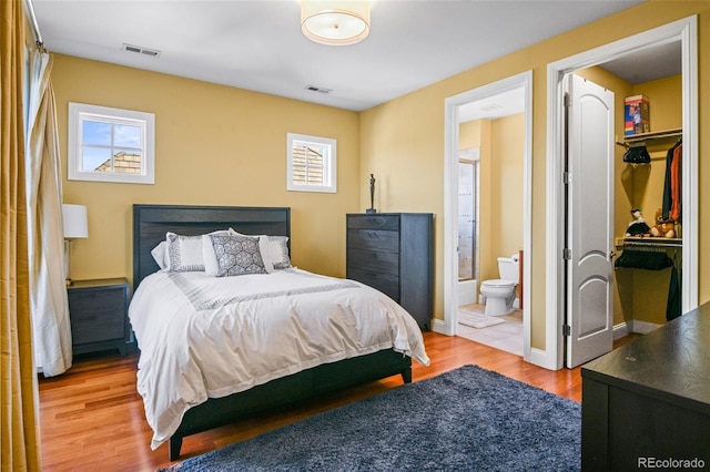 bedroom featuring a spacious closet, wood-type flooring, ensuite bath, and a closet