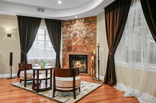 living area featuring light wood-type flooring, a fireplace, visible vents, and baseboards