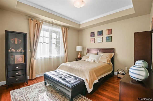 bedroom featuring ornamental molding, a tray ceiling, and dark wood finished floors