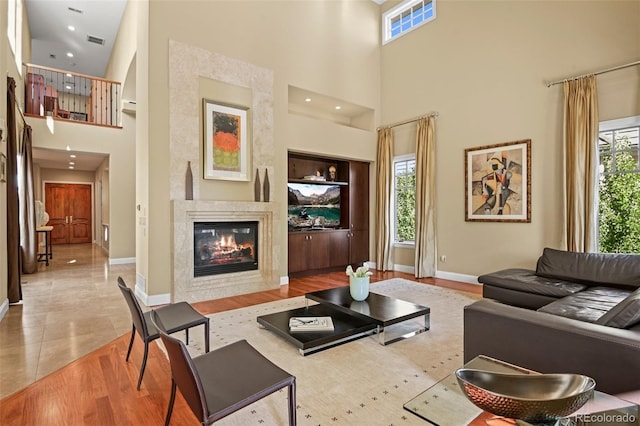 tiled living area featuring built in features, a glass covered fireplace, visible vents, and plenty of natural light