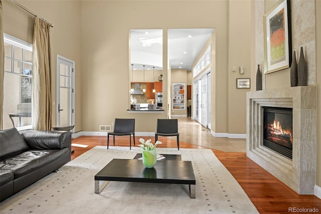 living room with wood finished floors, visible vents, baseboards, french doors, and a glass covered fireplace