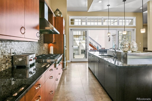 kitchen featuring tasteful backsplash, stainless steel gas stovetop, light tile patterned flooring, a sink, and wall chimney exhaust hood