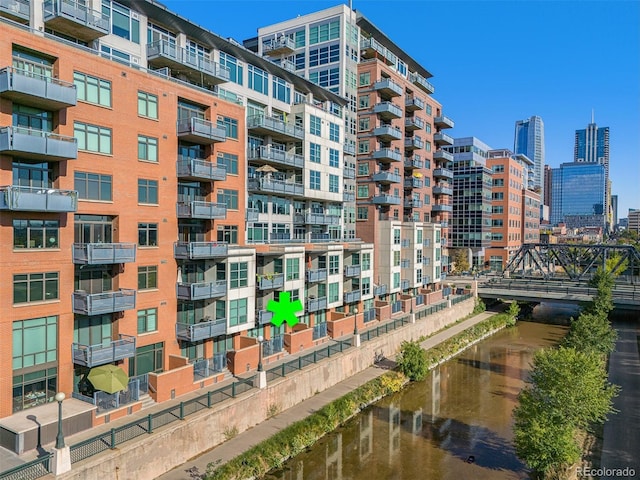 view of building exterior featuring a water view and a view of city