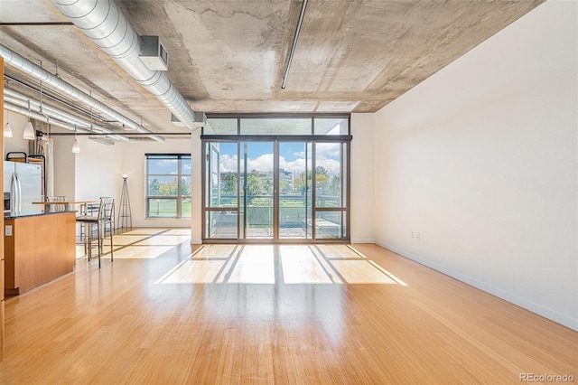 empty room featuring baseboards, expansive windows, and wood finished floors