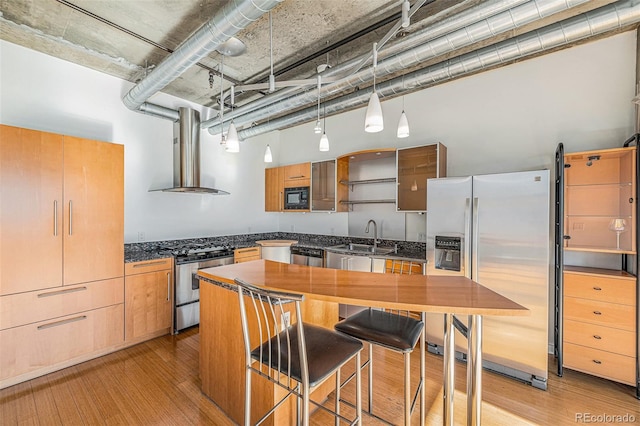 kitchen featuring wall chimney exhaust hood, stainless steel appliances, a sink, and dark countertops