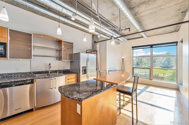kitchen with dark stone countertops, open shelves, a sink, light wood-style floors, and appliances with stainless steel finishes
