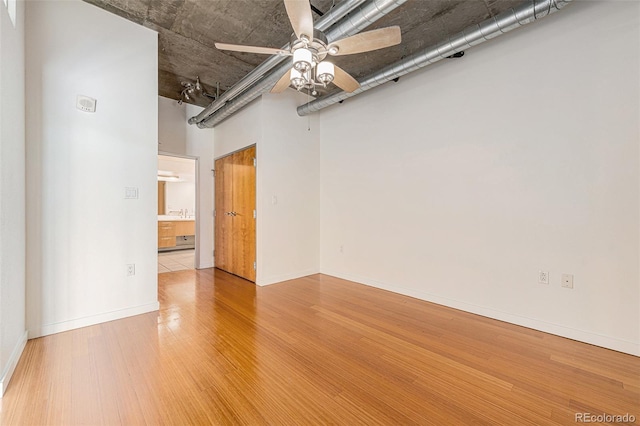spare room with wood finished floors, a ceiling fan, and baseboards