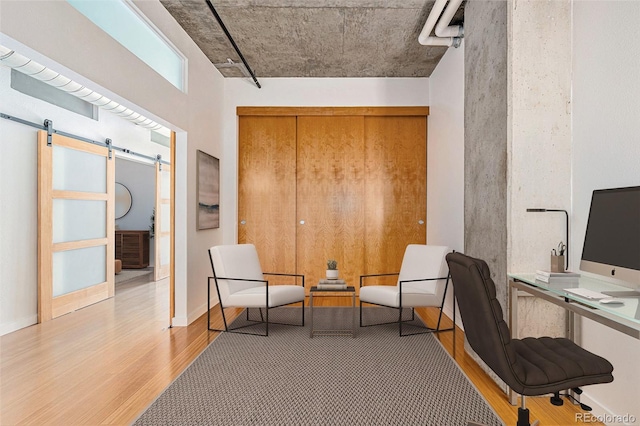 office featuring a barn door and light hardwood / wood-style flooring