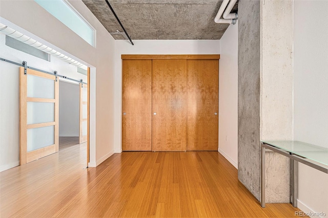 unfurnished bedroom with a barn door and wood finished floors