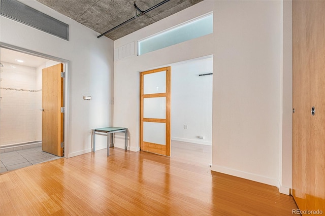 empty room with visible vents, wood finished floors, and a towering ceiling