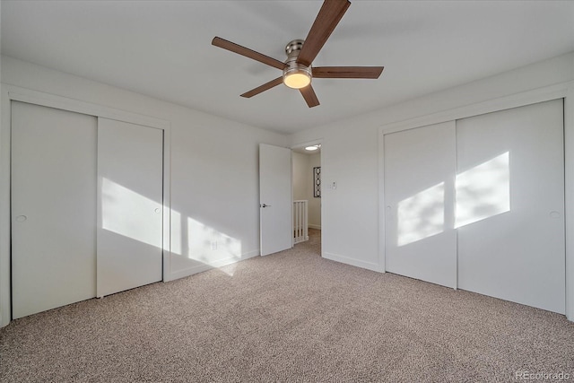 unfurnished bedroom with ceiling fan, multiple closets, and carpet flooring