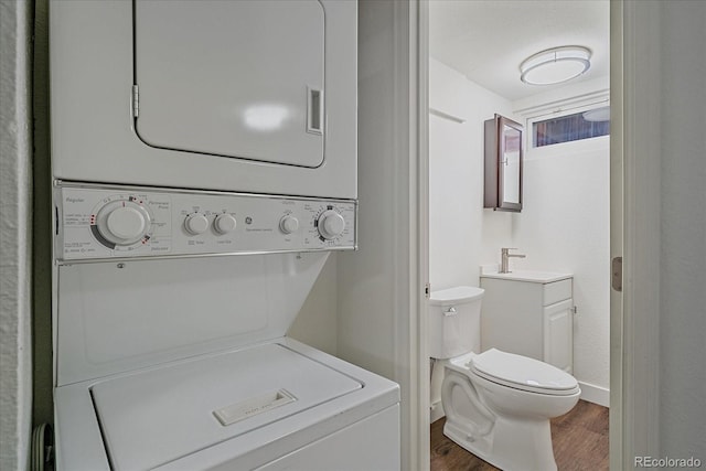 laundry room featuring stacked washer and dryer, dark wood-type flooring, and sink