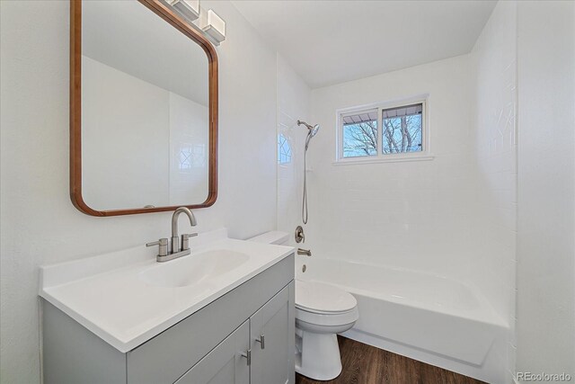 full bathroom featuring hardwood / wood-style flooring, washtub / shower combination, vanity, and toilet