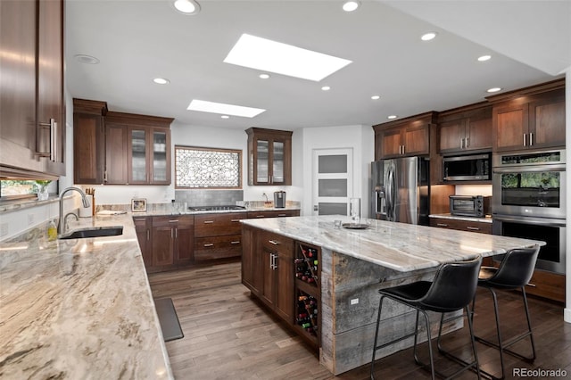 8453 S Scenic Dr, Morrison, CO 80465 - kitchen featuring appliances with stainless steel finishes, a sink, a breakfast bar, a kitchen island, and light stone counters