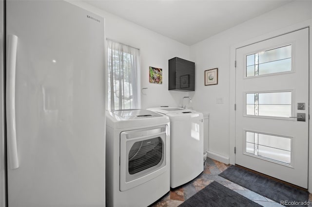 8453 S Scenic Dr, Morrison, CO 80465 - laundry area featuring washing machine and clothes dryer, plenty of natural light, dark stone finish floors, and baseboards