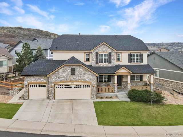 2463 Tavern Way, Castle Rock, CO 80104 - view of front facade with stone siding, stucco siding, covered porch, a garage, and driveway