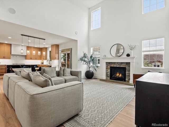 2463 Tavern Way, Castle Rock, CO 80104 - living area featuring light wood-style flooring, a towering ceiling, a stone fireplace, and recessed lighting