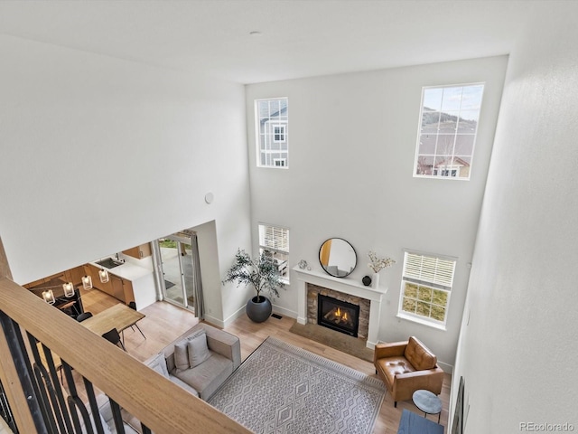 2463 Tavern Way, Castle Rock, CO 80104 - living room featuring light wood-type flooring, a glass covered fireplace, a towering ceiling, and baseboards