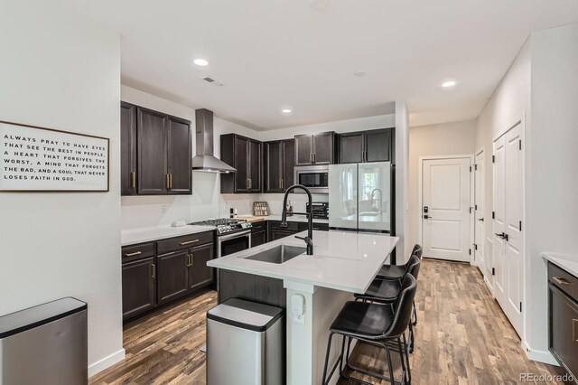 8433 Mount Kataka Loop, Littleton, CO 80125 - kitchen featuring a sink, wall chimney range hood, wood finished floors, light countertops, and appliances with stainless steel finishes