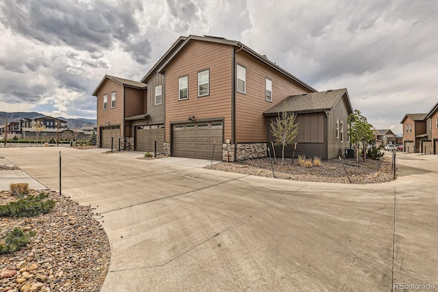 8433 Mount Kataka Loop, Littleton, CO 80125 - view of home's exterior with stone siding, a residential view, concrete driveway, a garage, and central AC unit