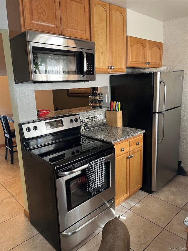 2285 S Jasper Way Unit A, Aurora, CO 80013 - kitchen featuring appliances with stainless steel finishes, light tile patterned floors, dark stone countertops, and a textured wall