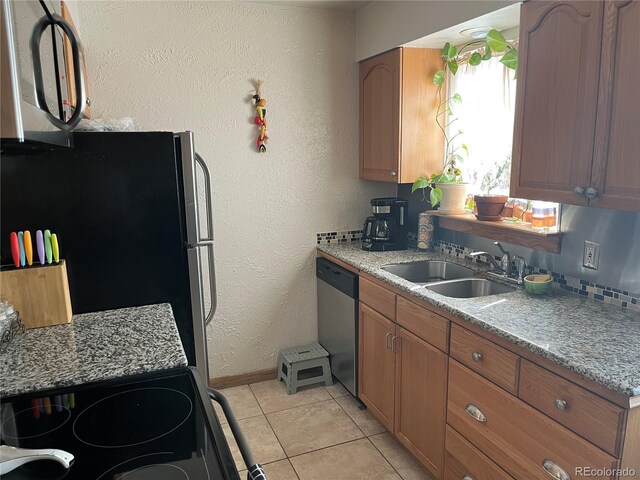2285 S Jasper Way Unit A, Aurora, CO 80013 - kitchen featuring appliances with stainless steel finishes, a sink, baseboards, brown cabinetry, and light tile patterned floors