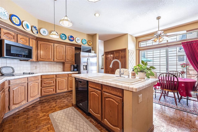 9873 Greensview Cir, Lone Tree, CO 80124 - kitchen with black appliances, a textured ceiling, decorative backsplash, an island with sink, and tile counters