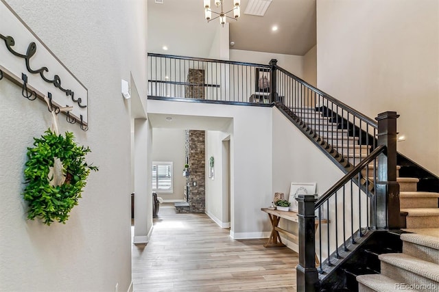 entrance foyer with an inviting chandelier, a towering ceiling, and light hardwood / wood-style floors