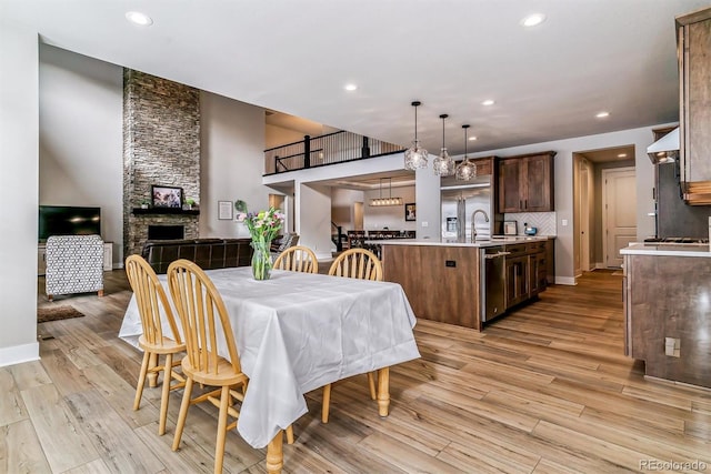 dining space featuring a stone fireplace, sink, and light hardwood / wood-style floors