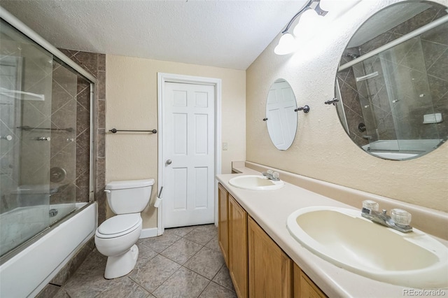 full bathroom with toilet, tile patterned floors, shower / bath combination with glass door, vanity, and a textured ceiling