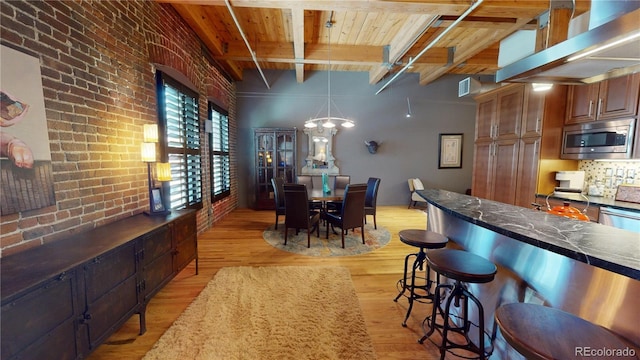 1745 Wazee St Unit 4H, Denver, CO 80202 - dining space featuring light wood-style floors, a wood ceiling with exposed beams, brick wall, and a chandelier