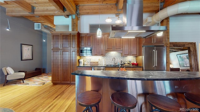 1745 Wazee St Unit 4H, Denver, CO 80202 - kitchen with stainless steel appliances, dark countertops, a breakfast bar, light wood finished floors, and island range hood