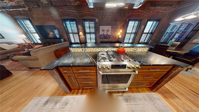 1745 Wazee St Unit 4H, Denver, CO 80202 - kitchen featuring stainless steel gas range, open floor plan, brown cabinetry, light wood-type flooring, and brick wall